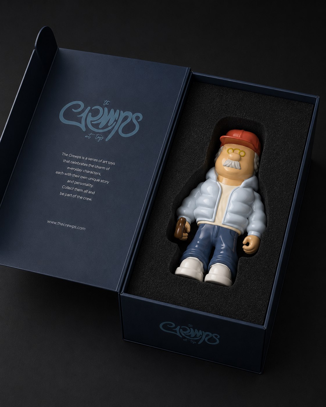 Packaging de The Grmps abierto: caja rígida azul noche con la figura en espuma troquelada